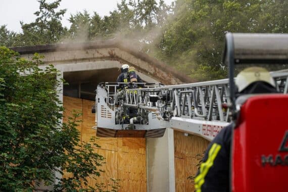 Feuerwehr löscht Brand in ehemaligem Schulgebäude, Feuerwehrleute im Einsatz, Rauchentwicklung sichtbar.