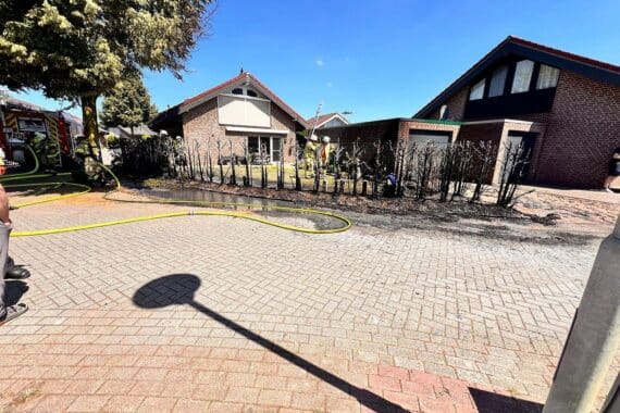 Feuerwehr löscht Heckenbrand, verhindert Übergreifen auf Garage, Einsatzkräft im Einsatz.