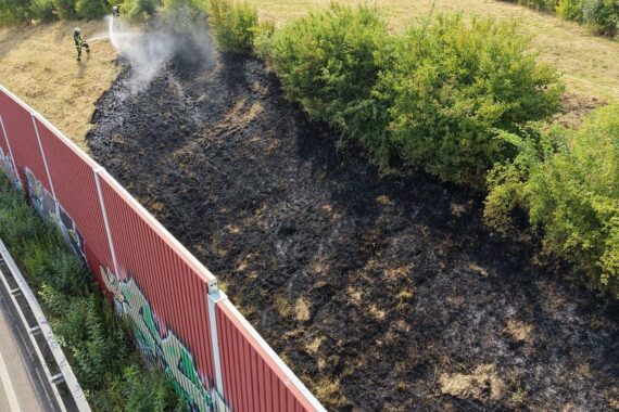 Feuerwehr Bochum löscht Böschungsbrand an der A40 bei Essen; Löschfahrzeuge, Rauch und Einsatzkräfte.