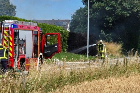 Feuerwehr löscht Heckenbrand; erhöhte Brandgefahr durch trockene Witterung. Sicherheitshinweise für Öffentlichkeit.