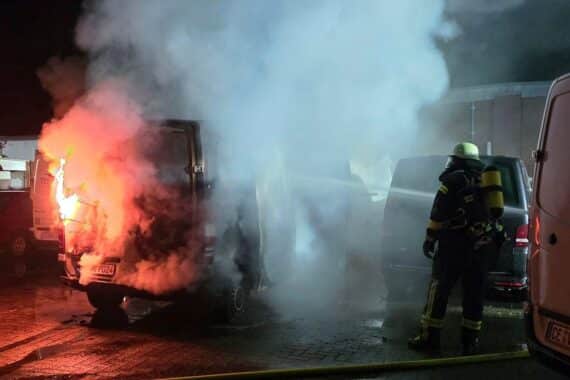 Brennende Kleintransporter auf einem Gewerbegelände, Feuerwehr im Einsatz zur Brandbekämpfung.