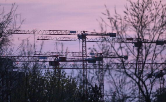 Baukräne am Bauplatz; Brandbrief wegen Kürzungen im Wohnungsbau an Kanzler Merz.