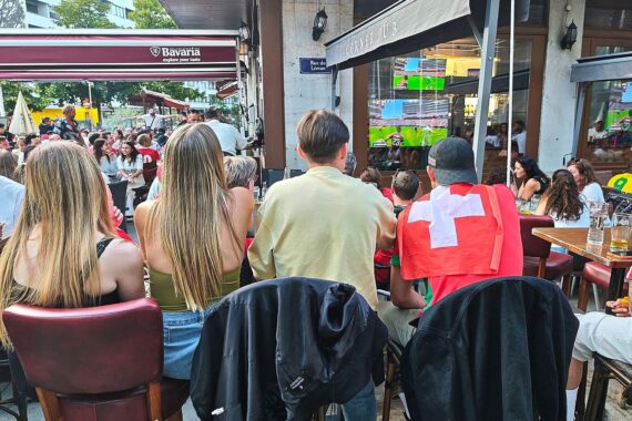 Fans schauen in einer Bar in Genf gespannt ein packendes Fußballspiel an.