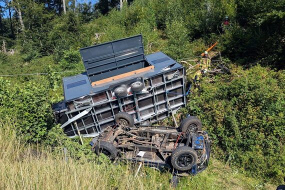 Feuerwehr-Einsatz nach Überschlag: Pkw mit Anhänger auf dem Dach in der Böschung, Fahrer eingeklemmt.