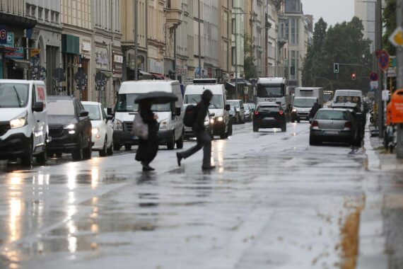 Straßenverkehr in Berlin-Kreuzberg bei wechselhaftem Wetter, Archivfoto, dichter Bewölkung und Regen-Symbolik.