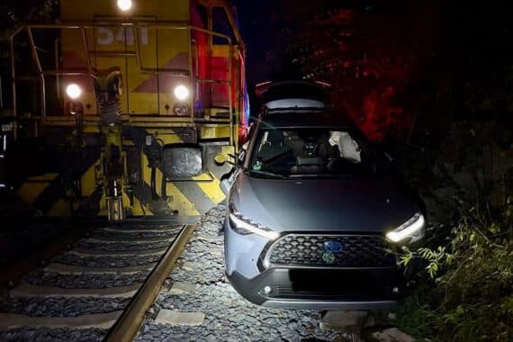 Unfallstelle am Bahnübergang in Ratingen: beschädigtes Auto nach Bahnunfall, Feuerwehr und Rettungskräfte vor Ort.