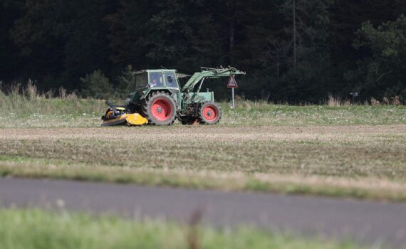 Bauer auf Traktor (Archiv) vor deutschem Feld, Hintergrund: Forderungen nach Soforthilfen wegen schlechter Ernte 2026.