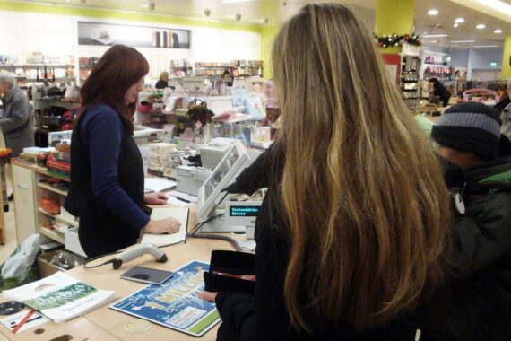 Kaufhaus-Kasse mit QR-Code auf Kundenbildschirm; Digitalbeleg statt Bonpflicht, neue Kassenvorschriften ab 2028.