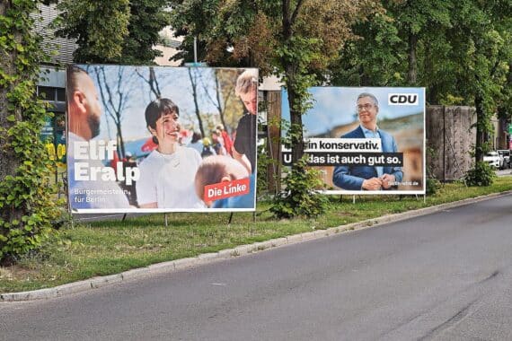 Elif Eralp spricht; Wahlplakate von Linkspartei und CDU in Berlin, Thema Vergesellschaftung großer Wohnungsbestände.