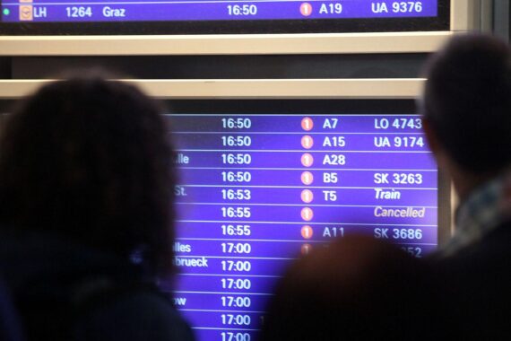 Passagiere am Frankfurter Flughafen, Infotafel im Hintergrund; Airport-Malaria: sechs infizierte Mitarbeiter, eine Person gestorben.