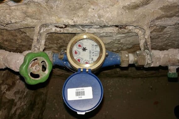 Absperrhahn und Wasseruhr im Altbaukeller—Symbol für Trinkwasserversorgung unter zunehmendem Grundwasserstress.