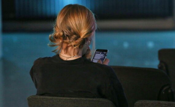 Junge Frau mit Smartphone: ChatGPT zeigt künftig Werbung in Deutschland, nicht personalisiert zu Beginn.