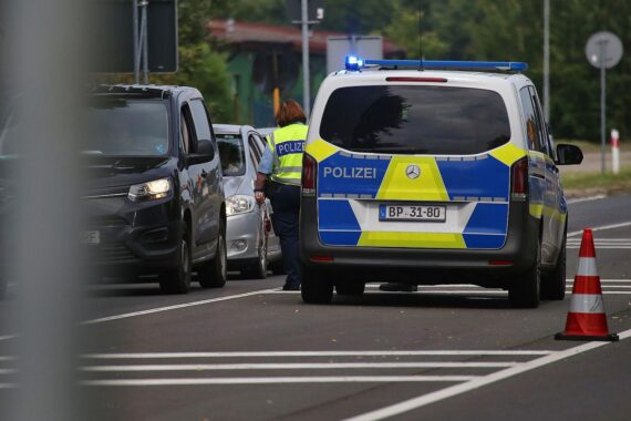 Deutsche Grenzkontrolle (Archiv): Polizisten an der Grenze, Überwachungstechnik, Migranten im Hintergrund.