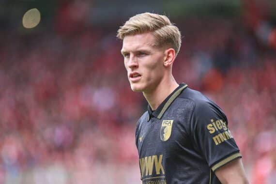 Fußballspieler (Anton Kade) jubeln vor dem FC Augsburg-Logo; Spiel: Augsburg gewinnt gegen Schalke 3:0.