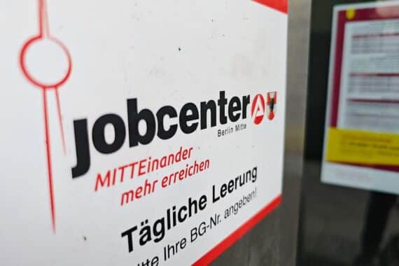 Jobcenter-Archivfoto: Menschen und Schalter, im Hintergrund ein Verwaltungsgebäude.