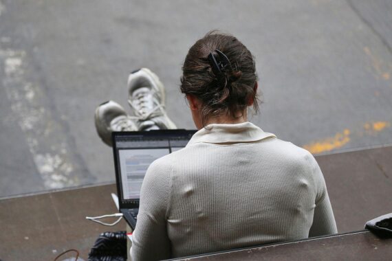 Frau mit Laptop im Büro; KI beeinflusst voraussichtlich Löhne in Deutschland, besonders bei Berufseinsteigern.