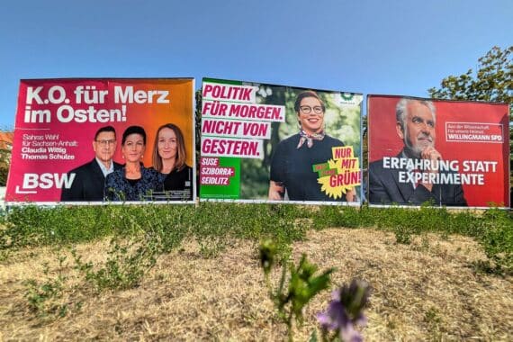 Wahlplakate in Sachsen-Anhalt vor Landtagswahl (Archiv), im Hintergrund Politiker-Porträts.
