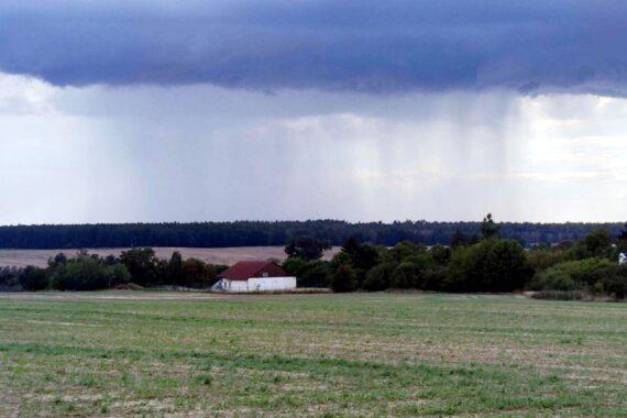 Unwetterwolke über einem Acker (Archiv), darüber teils Gewitter-/Schauergefahr, starke Wärme.