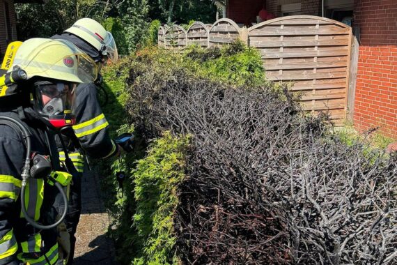 Atemschutzgeräteträger kontrolliert mit Wärmebildkamera eine bereits gelöschte Hecke in Aurich (Archiv).