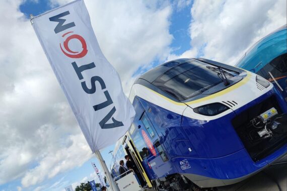 Nahaufnahme eines Alstom-Regionalzugs im Bild, Digitalisierung der Bahn und InnoTrans im Hintergrund.