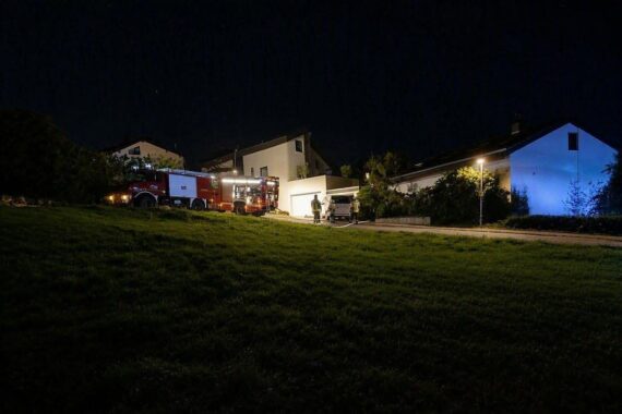 Feuerwehr-Einsatzfahrzeuge vor brennendem Holzunterstand in Weinheim-Steinklingen; Löscharbeiten in der Nacht.