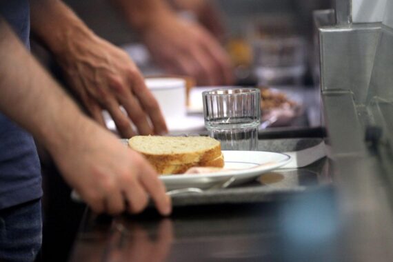 Frühstück in einer Kantine: Pausenbrot, Butter, Käse, Cerealien und Gemüse-Zutaten auf einem Tisch.