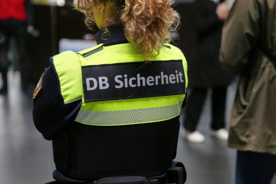 Person am Bahnhof; Bahn-Alkoholverbot-Schilder, Hinweis auf Regeln und Diskussion über Bahnhofskneipen.