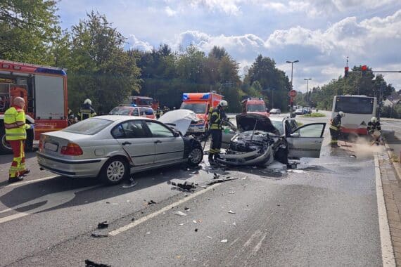 Unfall auf der Bochumer Straße: brennende Limousine, Feuerwehr bekämpft Feuer, Linienbus leicht beschädigt.