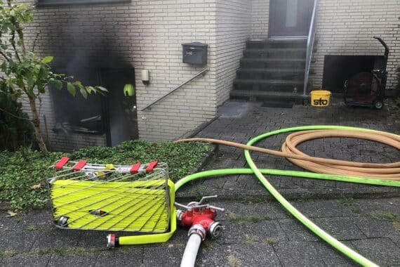 Feuerwehr Paderborn löscht Zimmerbrand in Souterrainwohnung im Archenholdweg; Einsatzkräfte und Rettungsdienst vor Ort.