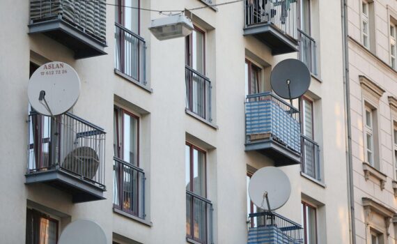 Satellitenschüssel an einem Wohnhaus; Archivfoto, politischer Streit um Mietgesetzespläne im Hintergrund.
