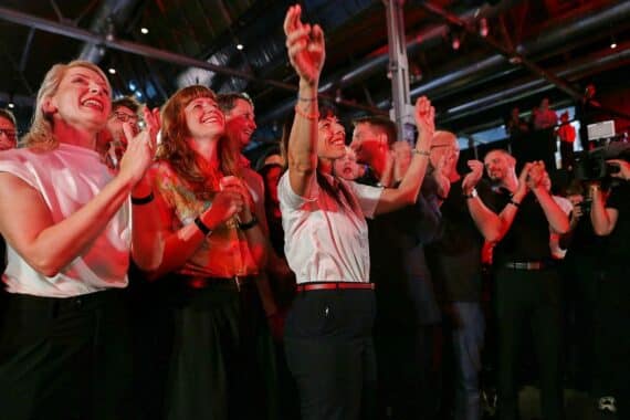 Linken-Wahlparty in Berlin: Menschen jubeln, Scheinwerfer und Partyatmosphäre, im Kontext Vergesellschaftungsdebatte.
