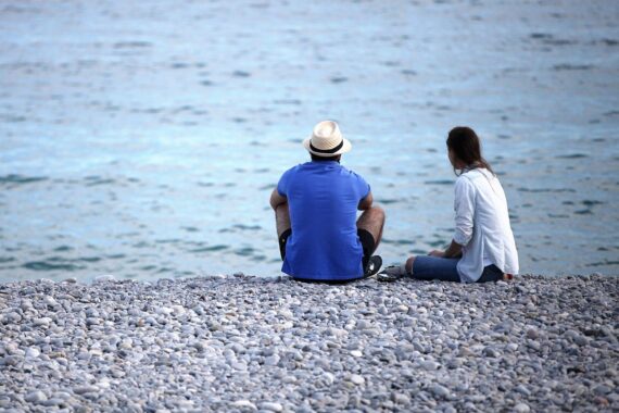 Mann und Frau sitzen am Strand; Thema: Lohnunterschiede zwischen Frauen und Männern in NRW.