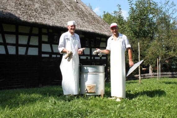 Schlachtfest im Museumsdorf: frische Würste und Kesselfleisch aus dampfenden Kesseln, historisches Treiben.
