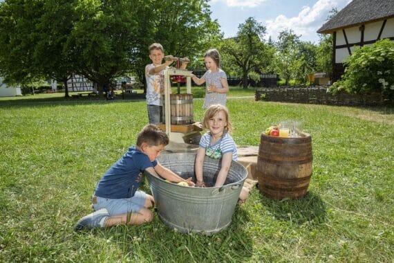 Kinder pressen eigenen Apfelsaft im Oberschwäbischen Museumsdorf Kürnbach, Tag der Deutschen Einheit.