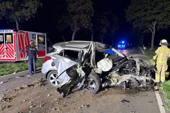 Schwer beschädigter Pkw nach Kollision mit Baum in Moers; Einsatzkräfte untersuchen die Unfallstelle.