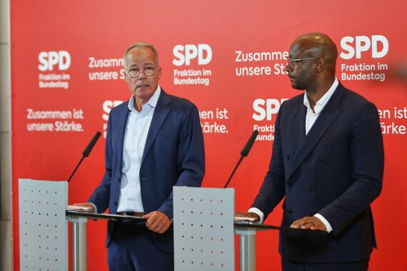 Matthias Miersch und Armand Zorn stehen im Gespräch vor einem politischen Hintergrund.