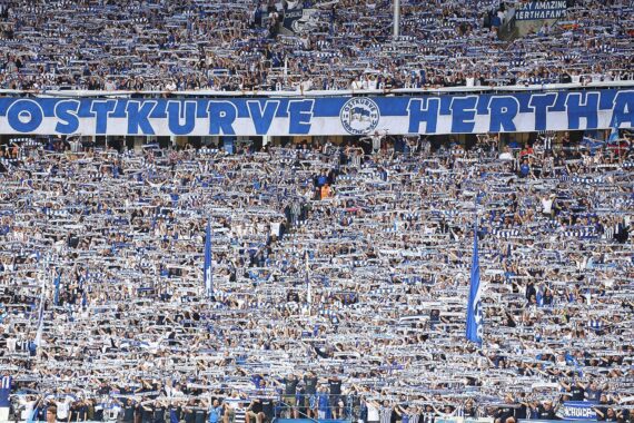 Hertha-Fans im Olympiapark vor Stadionkulisse: Hinweis auf Empfehlung für neues Fußballstadion.
