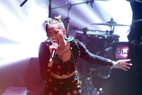 Miley Cyrus lächelt im Archivfoto; deutsche Musikcharts: Kissin’ Dynamite, Aymen, Matthias Reim, Miley, Anthrax.