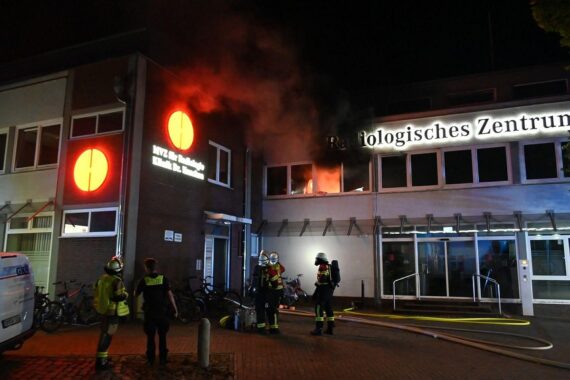 Wohnungsbrand in Mehrparteienhaus, Feuerwehr und Polizei im Einsatz; Rauchschaden am Gebäude, Rettungskräfte vor Ort.