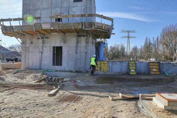 Bauarbeiter auf Baustelle (Archiv), vor modernen Betriebs- und Verwaltungsgebäuden in Nordrhein-Westfalen.