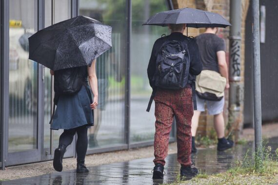 Personen mit Regenschirmen im Regen, wechselnd bis stark bewölkter Himmel über Thüringen (Archivfoto).