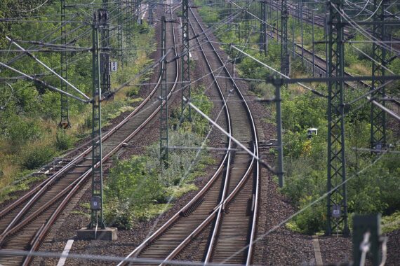 Bahngleise mit Oberleitungen; im Hintergrund mögliche Gefahrensituation für Personen im Gleisbereich (Archivfoto).