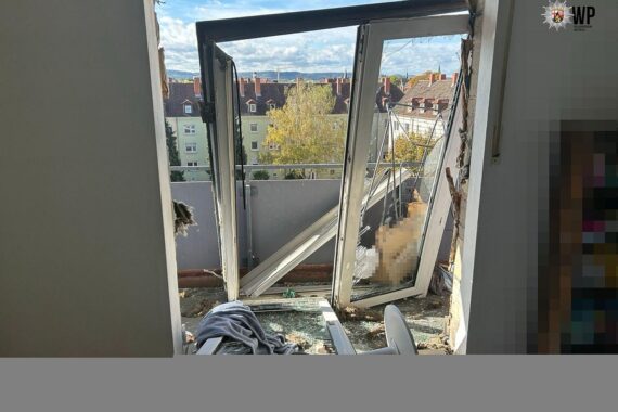 Zerstörte Wohnung nach mutmaßlicher Gasexplosion in Kaiserslautern, beschädigte Fenster und Einsatzkräfte.
