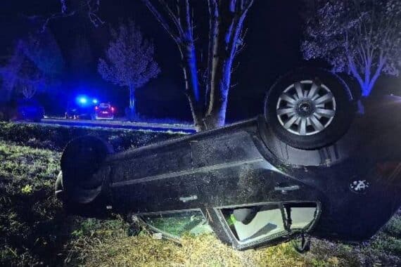 Ein beschädigter Pkw liegt nach einem Baumaufprall kopfüber im Straßengraben neben einer Landstraße.