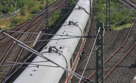 Ein ICE der Deutschen Bahn auf einer Bahnstrecke, umgeben von Gleisen und Oberleitungen.