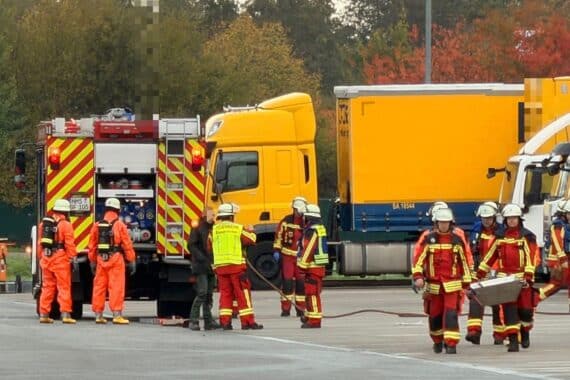 Feuerwehr im Einsatz: Einsatzkräfte mit Schutzanzügen, Gefahrgutaktion bei austretender Batteriesäure im Betrieb.