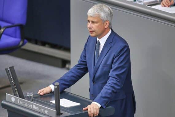 Steffen Bilger (CDU) vor Bahnhof, Deutsche Bahn Familienticket, Familien auf Reisen im Hintergrund.