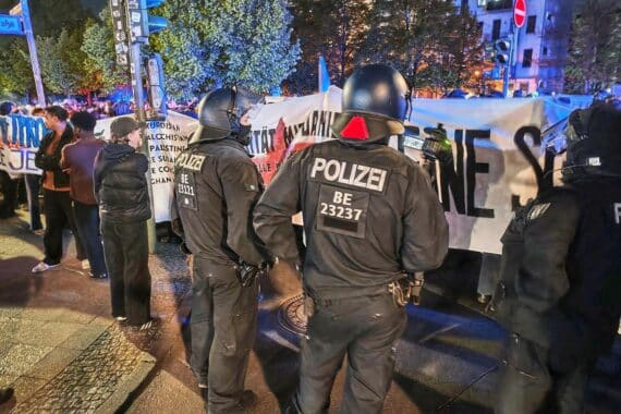 Demonstrierende mit Transparenten und Fahnen bei einer linken Protestkundgebung in Berlin.