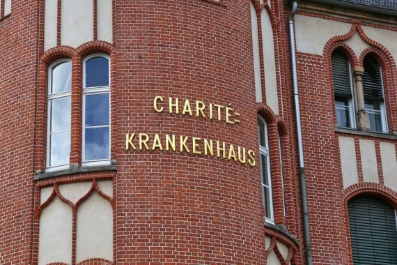 Charité-Logo und Krankenhausgebäude in Berlin (Archivfoto), über Bürokratiekosten im Gesundheitswesen.