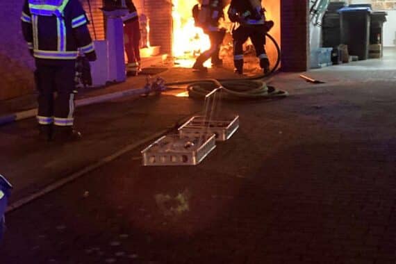 Feuerwehrkräfte unter Atemschutz löschen eine brennende Garage neben einem Wohnhaus in Bergheim-Quadrath-Ichendorf.